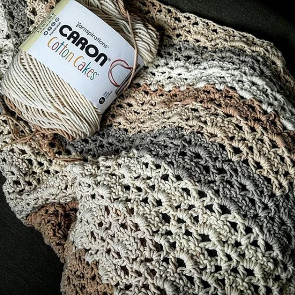 Image of 1 skein of Caron Cotton Cakes in Garden Path on top of the Reverie triangle shawl in progress.