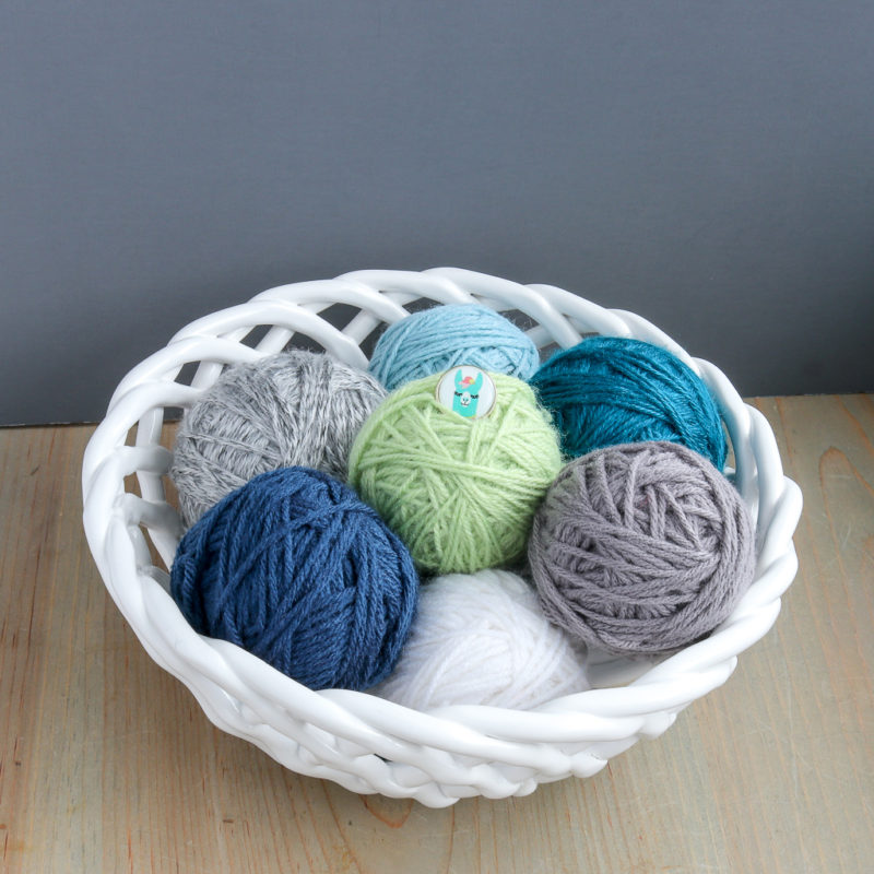 Several balls of yarn displayed in a ceramic bowl