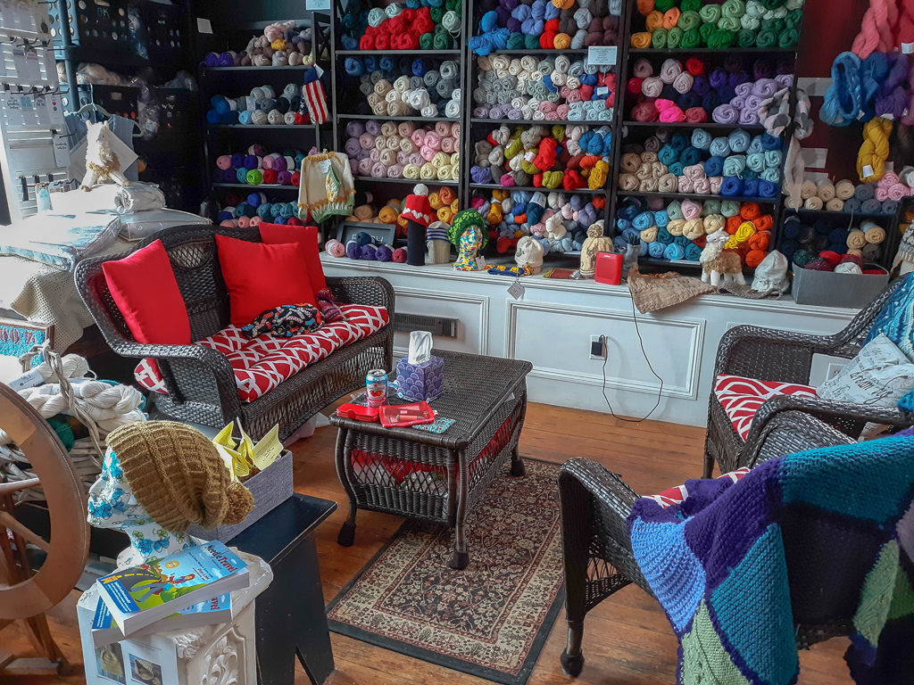 Image of couch, coffee table, and chairs surrounded by yarn
