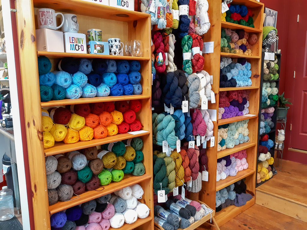 Image of yarn displayed on shelves and hanging on the wall