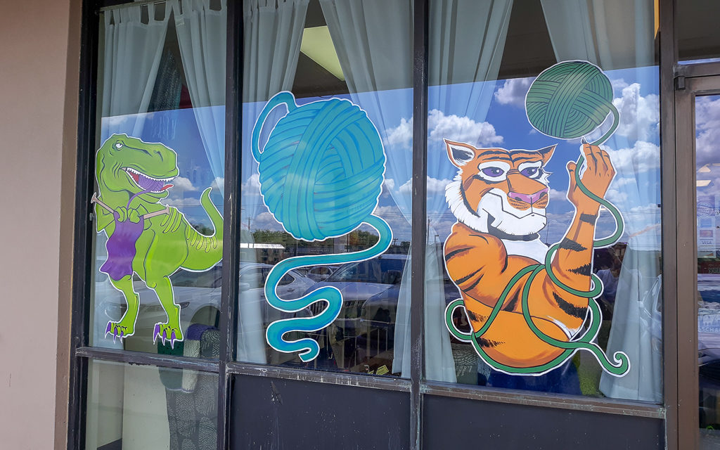 Image of Yarnivore Storefront of a tiger, t-rex, and ball of yarn
